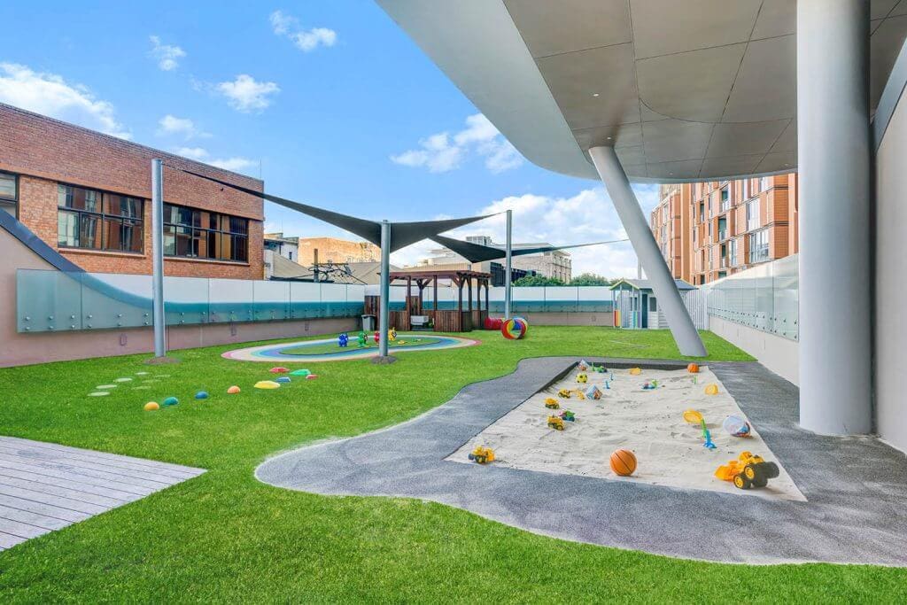 Outdoor learning area at Wonder Garden Learning Center with vibrant artificial grass in rainbow colors